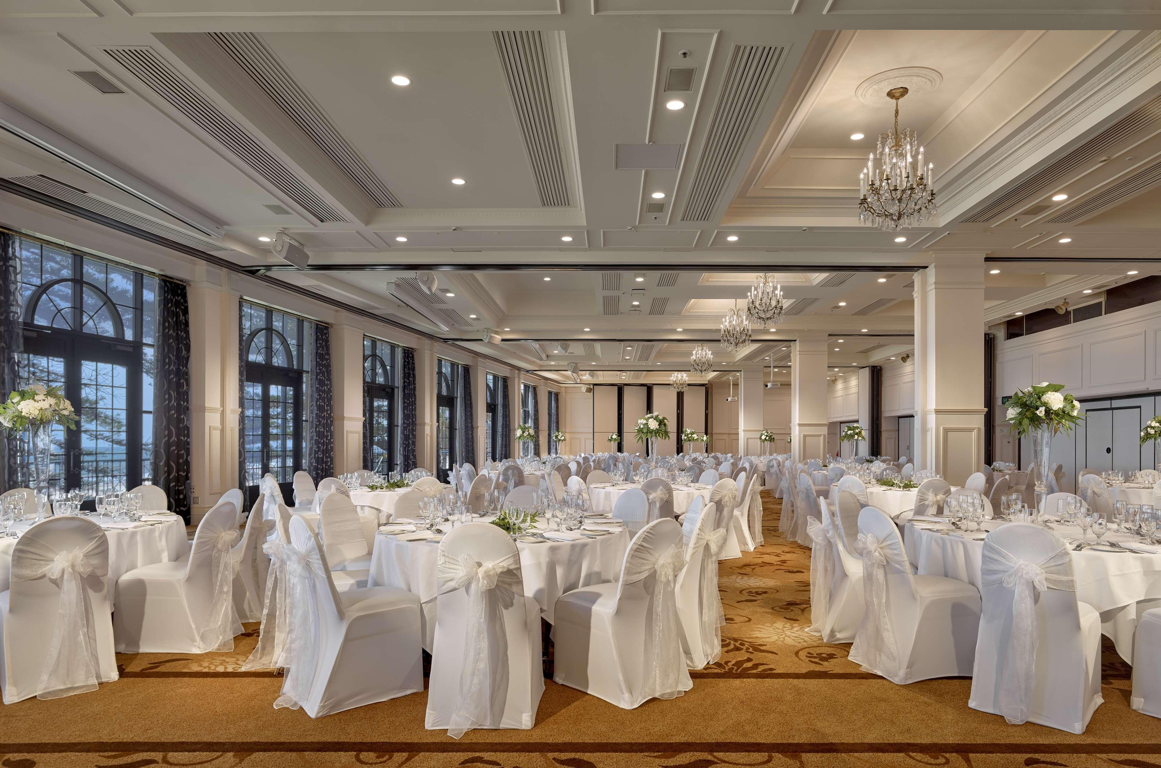 Stamford Grand Adelaide Hotel Гленелг Екстериор снимка The photo depicts an elegantly arranged banquet hall or dining area. The space features multiple round tables, each set with white tablecloths and decorated with floral centerpieces. The chairs are covered in white fabric, contributing to a formal at