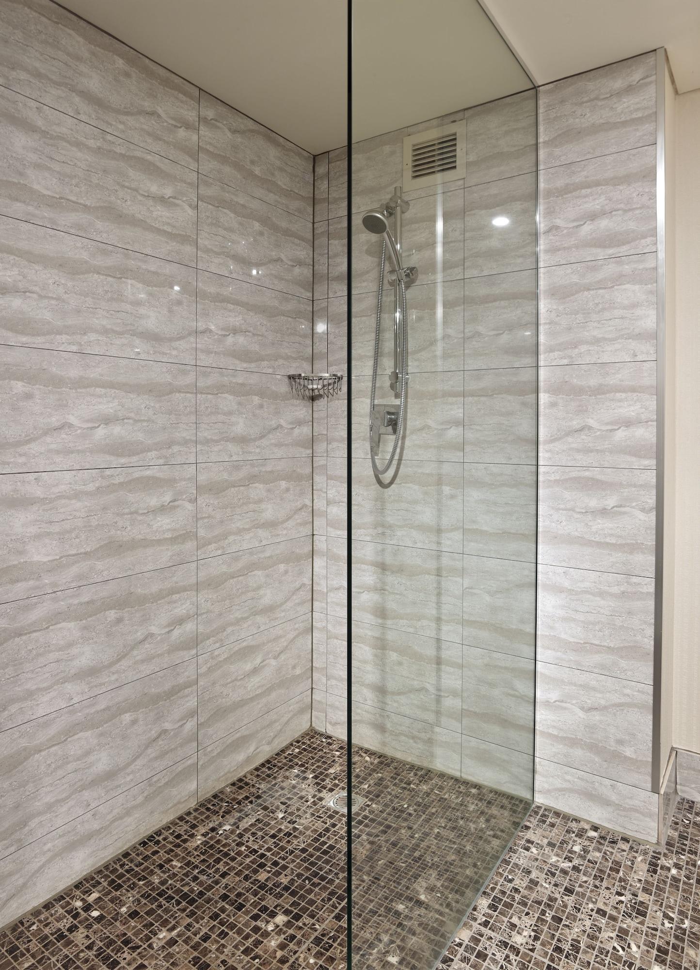 Stamford Grand Adelaide Hotel Гленелг Екстериор снимка The photo shows a modern shower enclosure with a transparent glass door. The interior features tiled walls in a light, marble-like pattern, creating a clean and sleek look. There is a showerhead mounted on the wall, and the floor appears to be tiled 