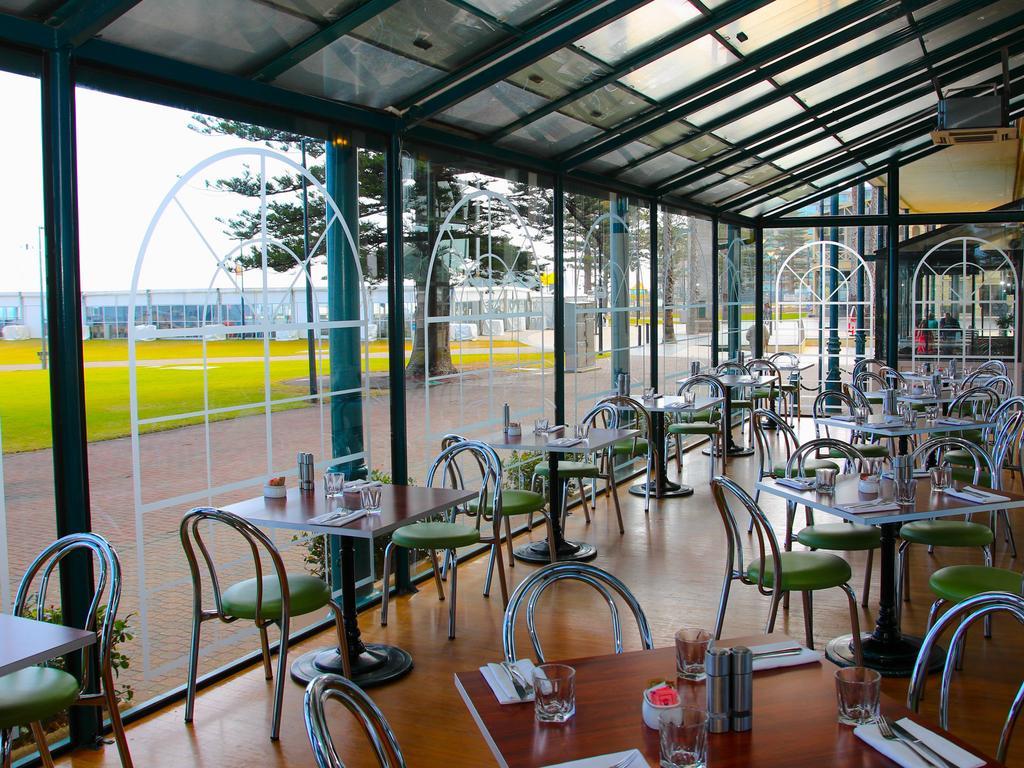Stamford Grand Adelaide Hotel Гленелг Екстериор снимка The photo shows the interior of a restaurant with a modern design. The space features several tables with green chairs, arranged in a way that allows for ample seating. Large glass windows provide a view of the outside, creating a bright and open atm