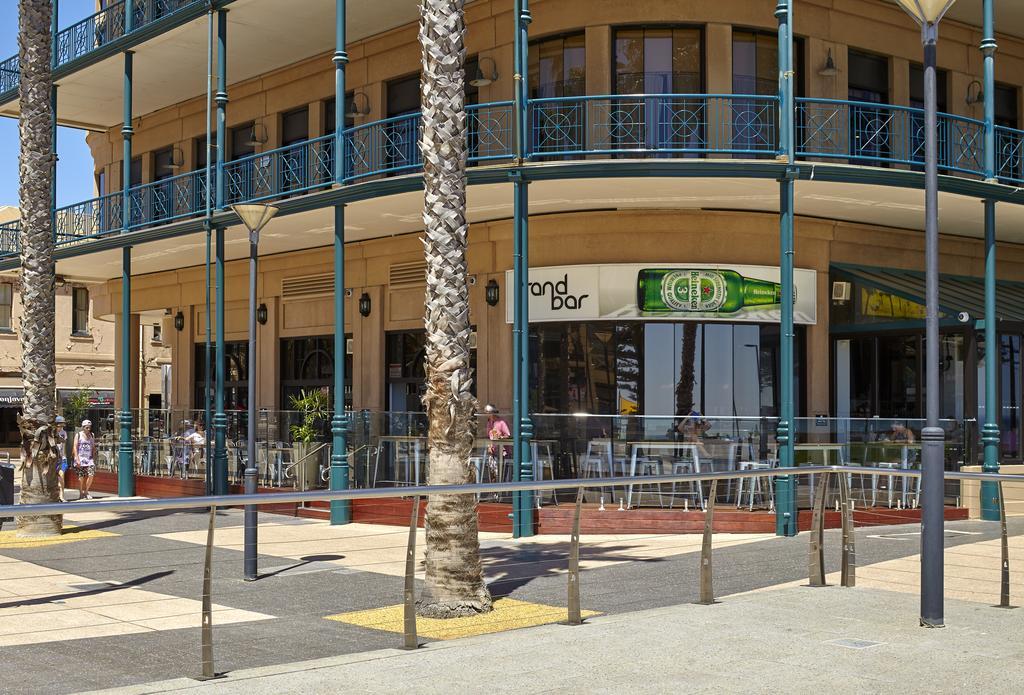 Stamford Grand Adelaide Hotel Гленелг Екстериор снимка The photo shows a corner of a building that houses a bar with the name "End Bar" prominently displayed. It's a multi-level structure with balconies featuring decorative railings. In front of the bar, there are tables and chairs, indicating a dining o