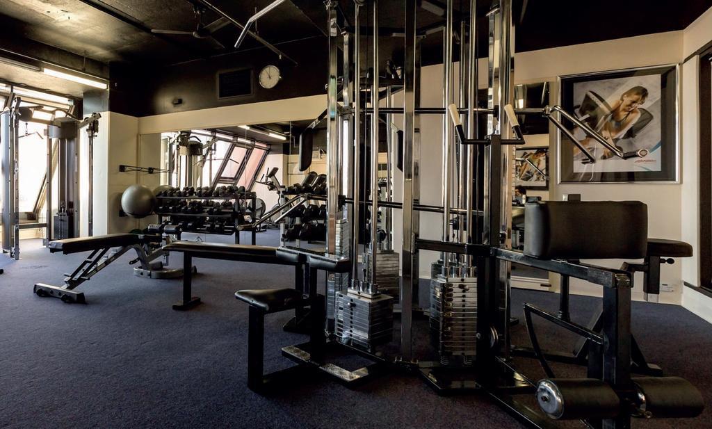 Stamford Grand Adelaide Hotel Гленелг Екстериор снимка The photo shows a gym interior with several pieces of exercise equipment. In the foreground, there is a multi-station machine that features various pulleys and weights. To the side, there are benches and free weights, including dumbbells. The gym has