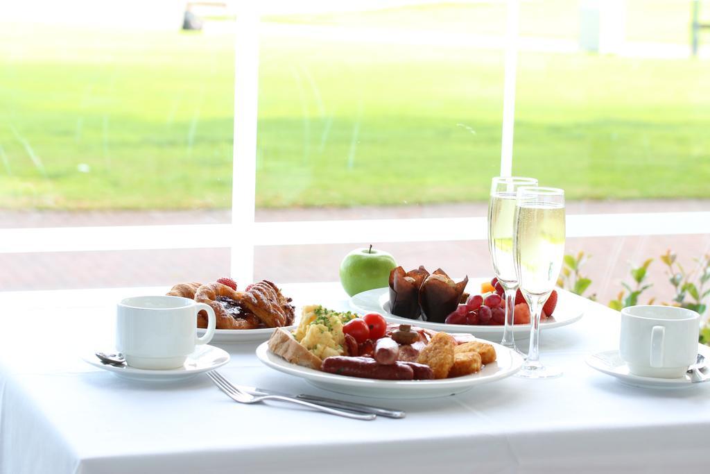 Stamford Grand Adelaide Hotel Гленелг Екстериор снимка The photo displays a beautifully arranged breakfast setup on a white tablecloth. In the center, there is a large white plate with a variety of foods, including eggs, sausage, and fresh fruit. Surrounding the plate are a few other food items, such as 