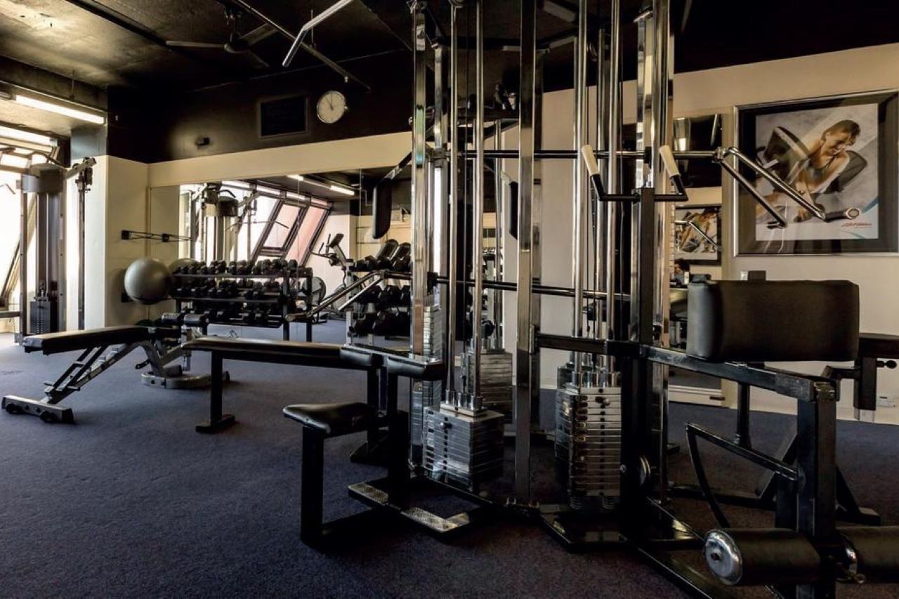 Stamford Grand Adelaide Hotel Гленелг Екстериор снимка The photo shows a gym interior with various exercise equipment. In the foreground, there is a multi-station cable machine, which has several adjustable weights and pulleys for a variety of strength training exercises. To the side, there's a bench and